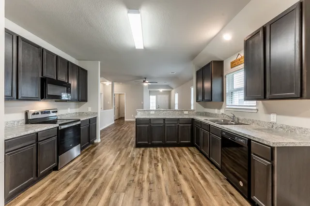 a large kitchen with stainless steel appliances granite countertop a stove refrigerator and microwave