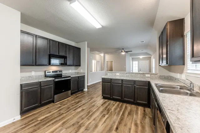 a large kitchen with stainless steel appliances granite countertop a sink stove and refrigerator