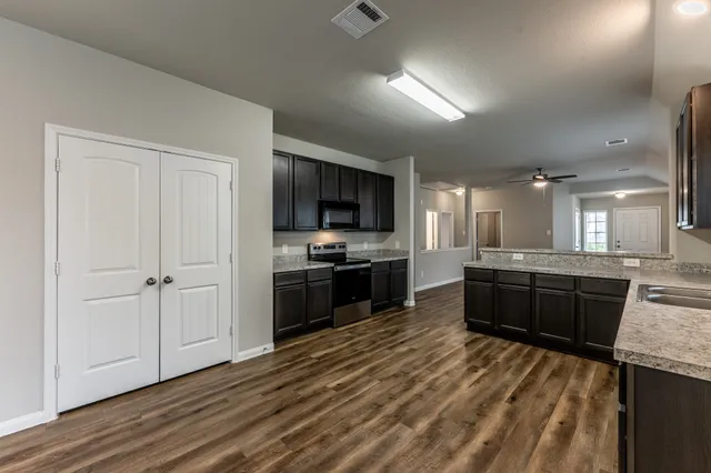 a large kitchen with a stove a sink dishwasher a refrigerator and a oven with wooden floor