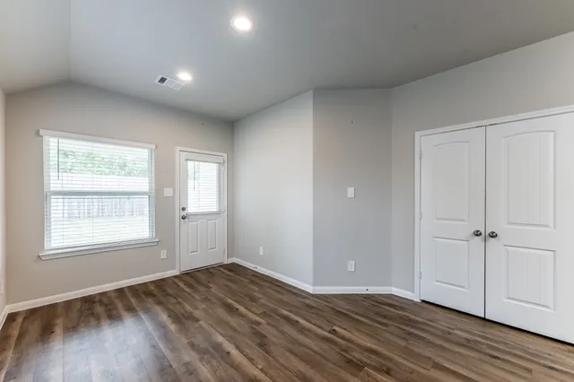 an empty room with wooden floor and window