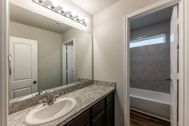 a bathroom with a granite countertop sink a mirror and a bathtub