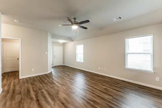 a view of an empty room with a window and wooden floor