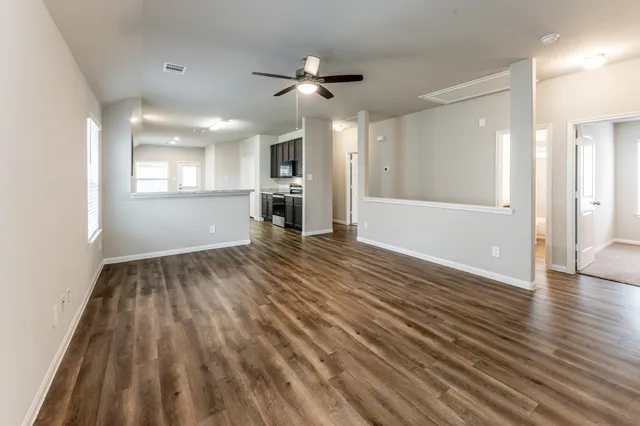 a view of empty room with wooden floor and fan