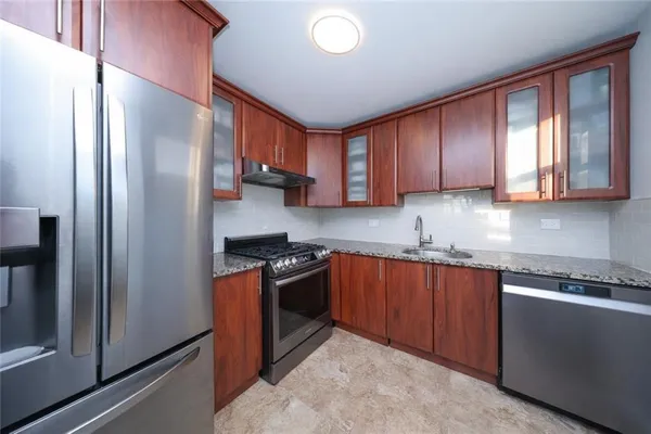 a kitchen with stainless steel appliances granite countertop a refrigerator a sink and wooden cabinets