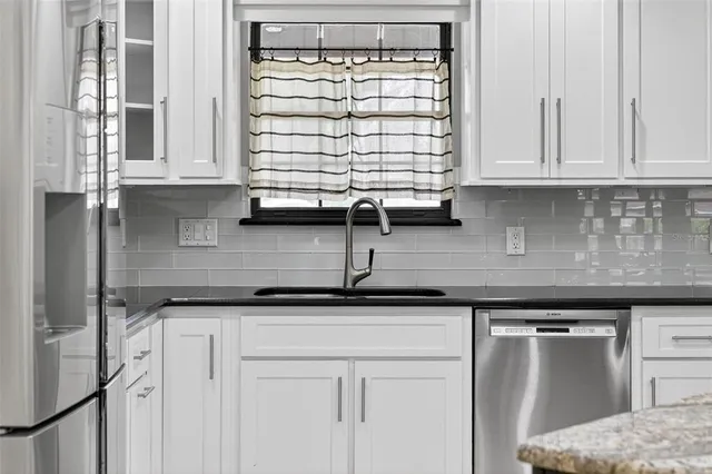 a large white kitchen with a large counter top and stainless steel appliances