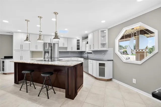 a kitchen with stainless steel appliances kitchen island a table chairs in it and white cabinets