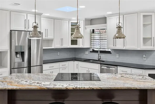 a kitchen with stainless steel appliances granite countertop a table chairs in it and wooden floors