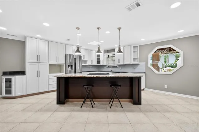 a large kitchen with stainless steel appliances a large counter top a stove a refrigerator and a sink