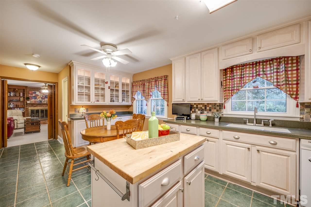 4616 Fernham Place Raleigh, NC 27612 - Photo 3 of 26 a kitchen with a stove a sink a dining table and chairs