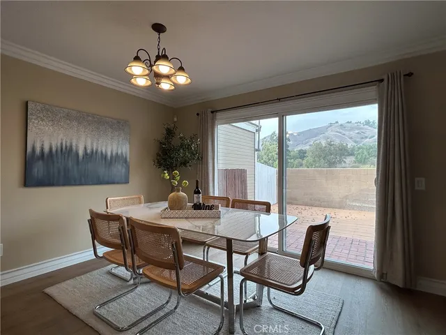 a dining room with wooden floor a chandelier a glass table and chairs