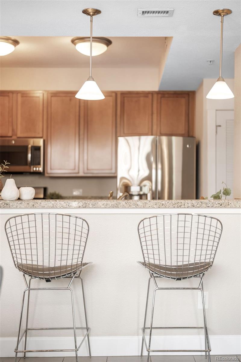 1699 North Downing Street, Unit 306 Denver, CO 80218 - Photo 11 of 26 a kitchen with stainless steel appliances granite countertop a dining table chairs and a white refrigerator