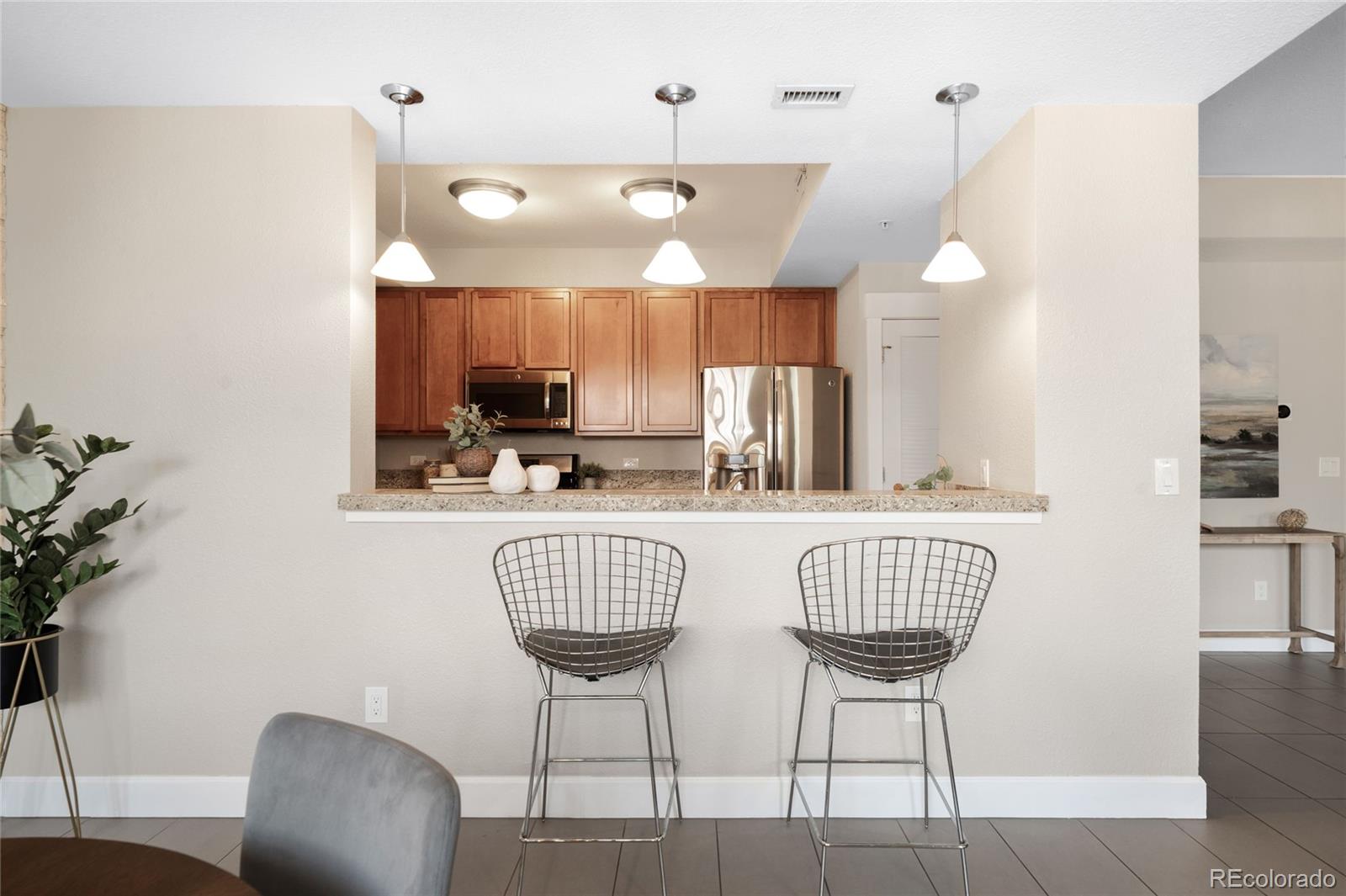 1699 North Downing Street, Unit 306 Denver, CO 80218 - Photo 10 of 26 a kitchen with stainless steel appliances kitchen island granite countertop a dining table chairs and a refrigerator