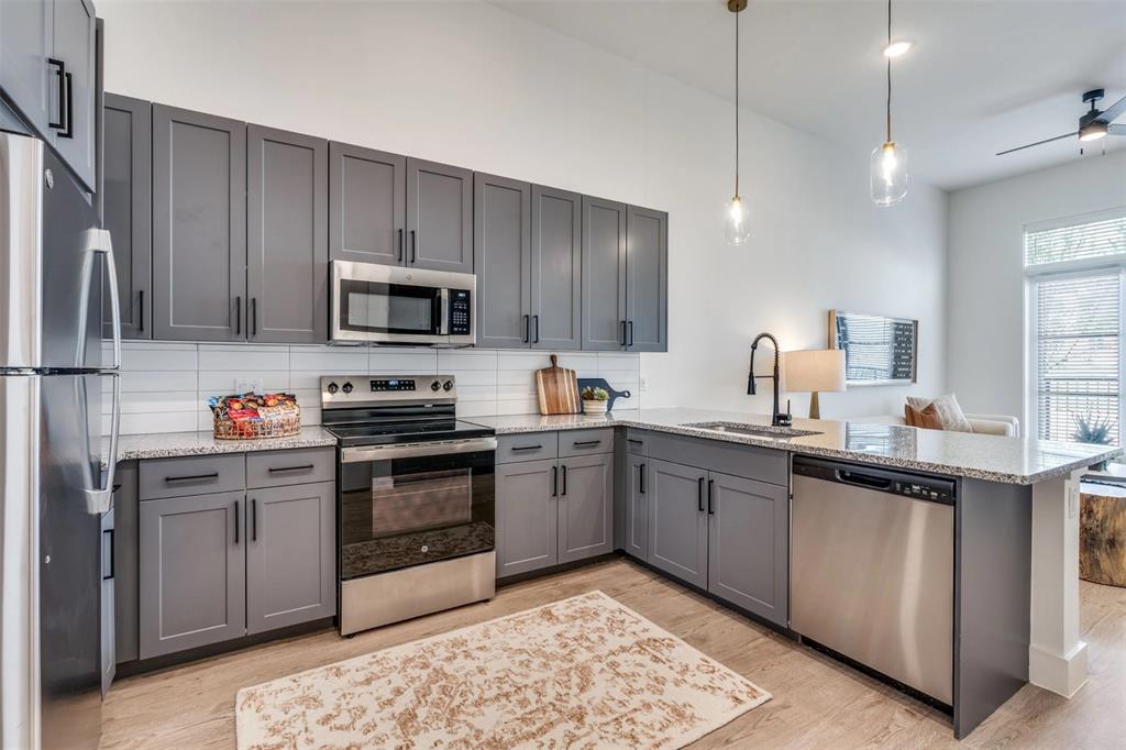 650 East Sycamore Street, Unit 1151 Denton, TX 76205 - Photo 9 of 19 a kitchen with stainless steel appliances granite countertop a stove top oven a sink and dishwasher a refrigerator with wooden floor