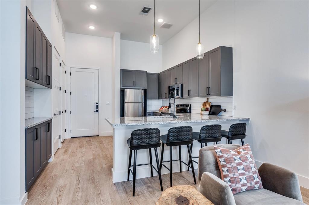 650 East Sycamore Street, Unit 1151 Denton, TX 76205 - Photo 10 of 19 a kitchen with stainless steel appliances kitchen island granite countertop a stove a sink a refrigerator and chairs
