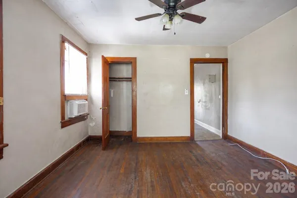 an empty room with wooden floor fan and windows