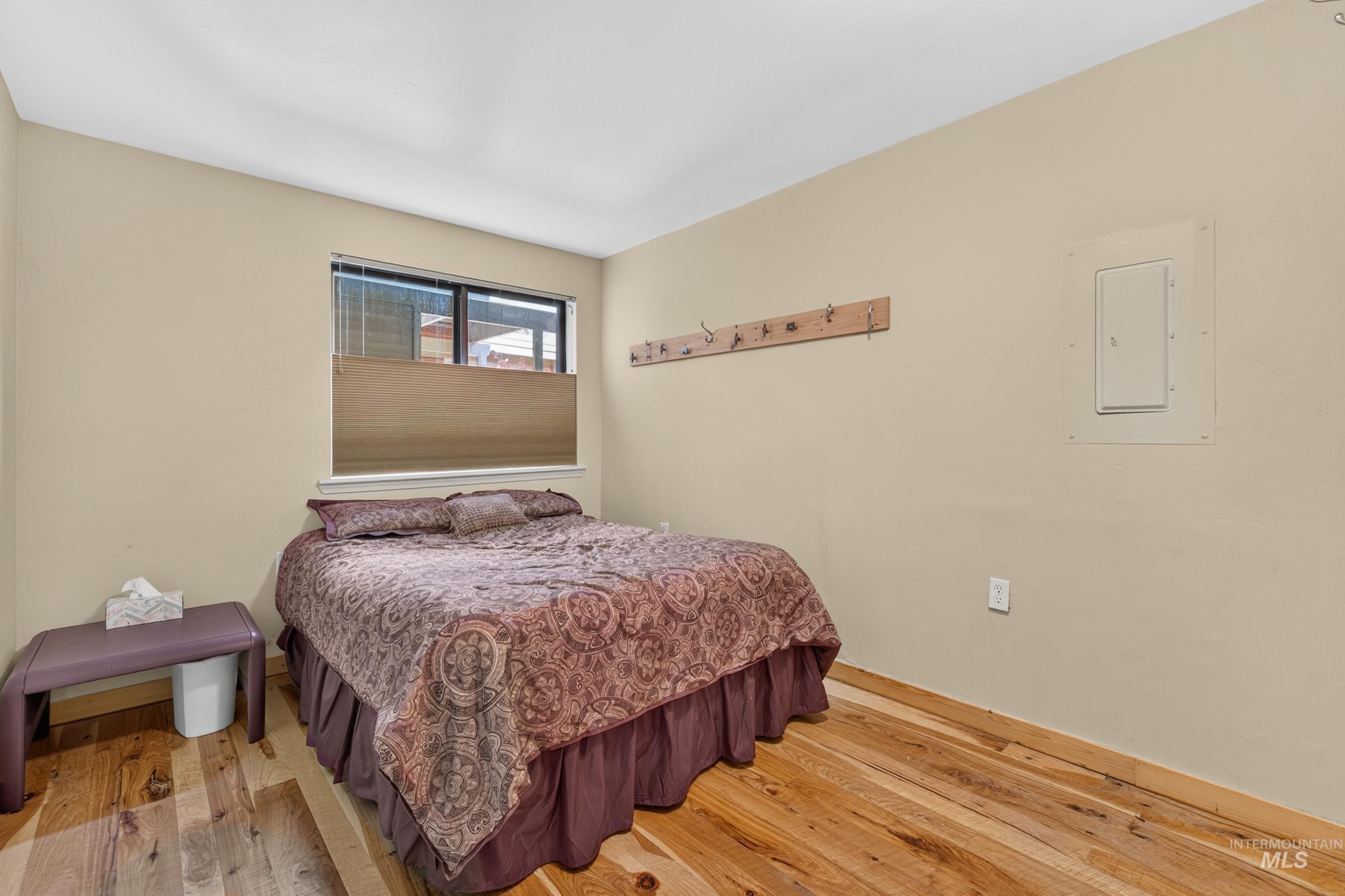 302 Mather Road McCall, ID 83638 - Photo 12 of 24 Hardwood flooring, neutral wall tones, window with pleated shades, integrated wall outlet, and a wall-mounted coat rack