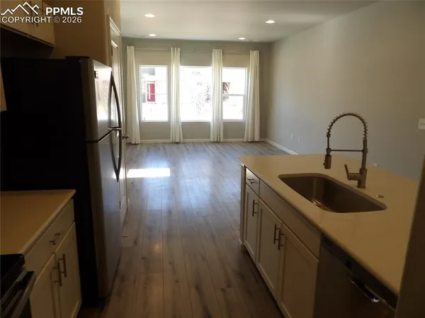a kitchen with stainless steel appliances granite countertop a refrigerator a sink a stove and wooden floor