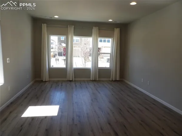 an empty room with wooden floor and windows
