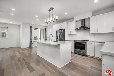 a kitchen with stainless steel appliances a white stove top oven cabinets and a wooden floor