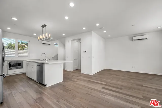 a kitchen with stainless steel appliances kitchen island wooden floors and white cabinets