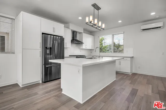 a kitchen with stainless steel appliances a refrigerator sink and wooden floor