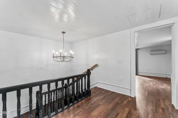 a view of a hallway with wooden floor and chandelier