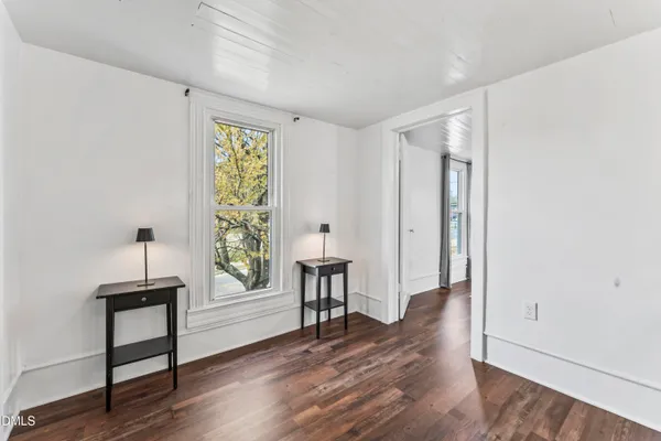 a view of an empty room with window wooden floor and front door