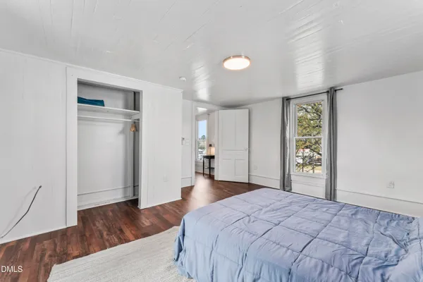 a bedroom with a large bed and wooden floor