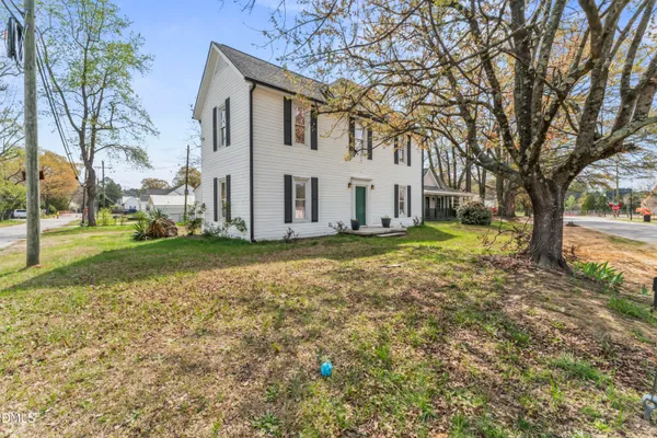 a view of a white house with a large tree in front of it