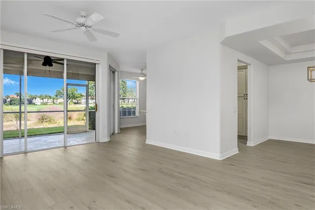 an empty room with wooden floor fan and windows