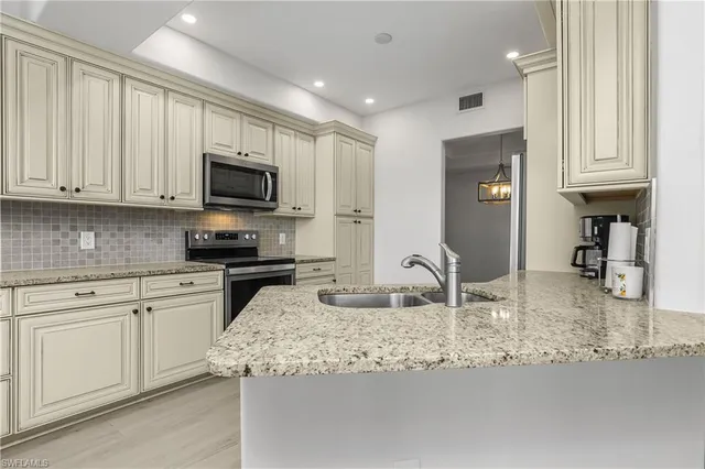 a kitchen with granite countertop a sink white cabinets and stainless steel appliances