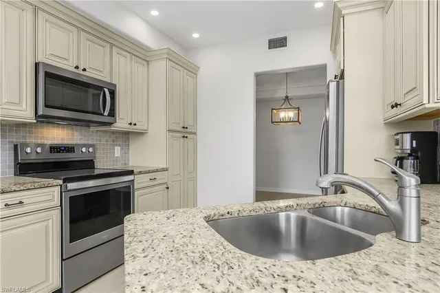 a kitchen with stainless steel appliances granite countertop a sink a stove and microwave