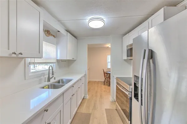 a kitchen with stainless steel appliances granite countertop a refrigerator a sink and white cabinets
