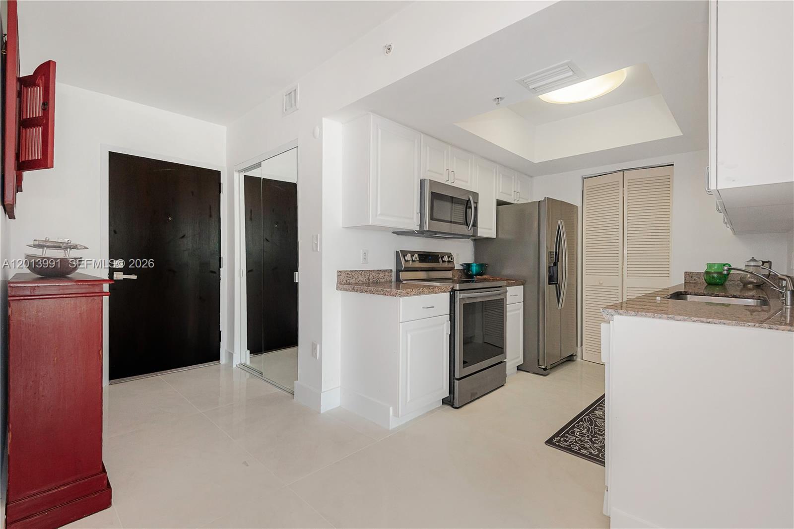 90 Alton Road, Unit 1007 Miami Beach, FL 33139 - Photo 11 of 25 a kitchen with a refrigerator a sink a stove and cabinets