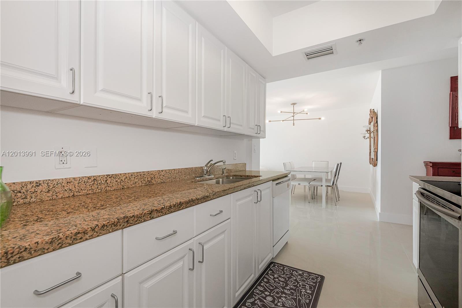 90 Alton Road, Unit 1007 Miami Beach, FL 33139 - Photo 14 of 25 a kitchen with granite countertop white cabinets and white appliances