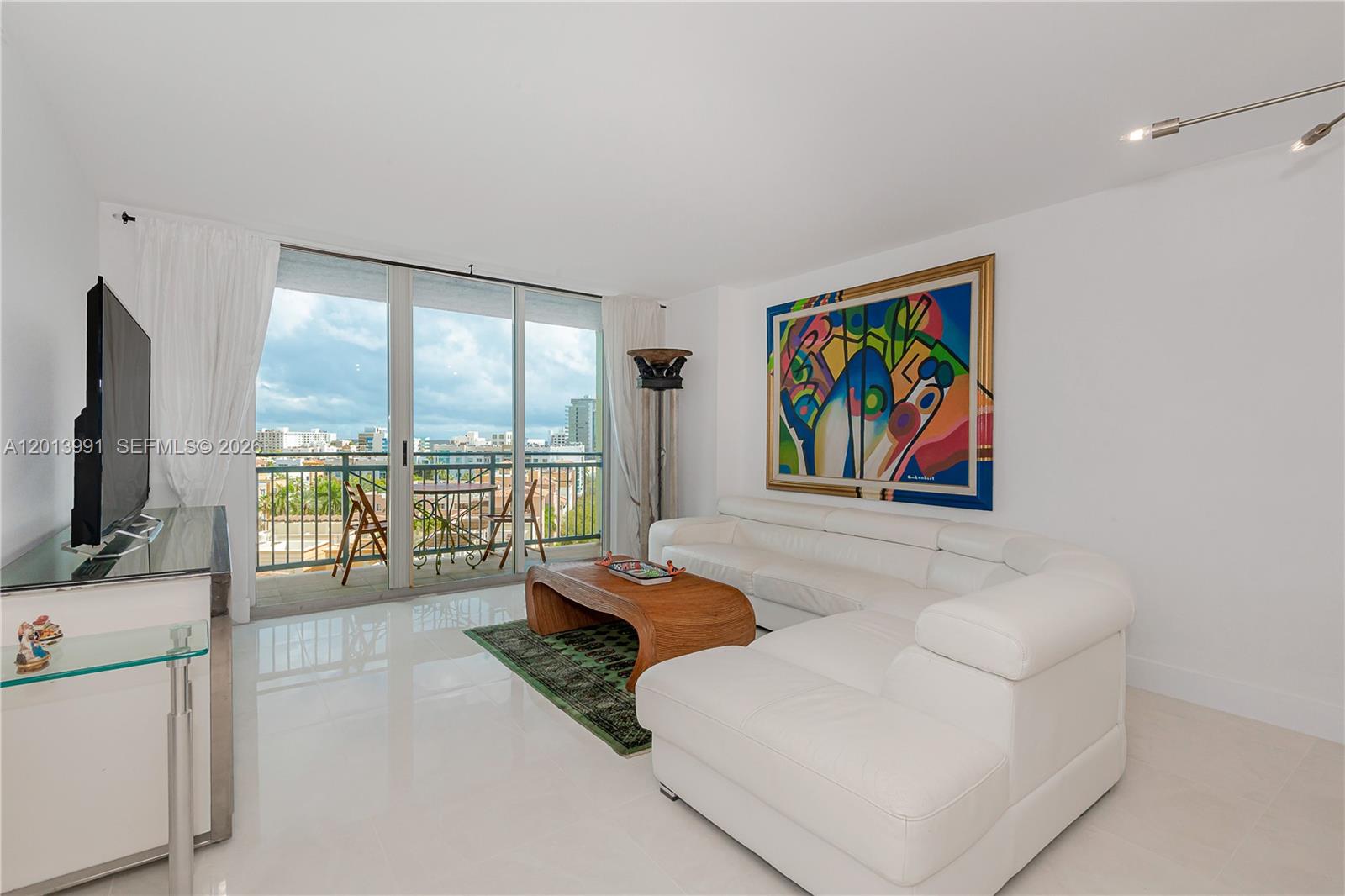90 Alton Road, Unit 1007 Miami Beach, FL 33139 - Photo 4 of 25 a living room with furniture a flat screen tv and a floor to ceiling window