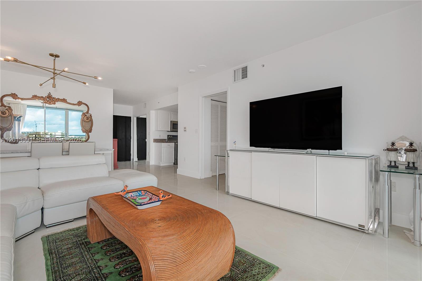 90 Alton Road, Unit 1007 Miami Beach, FL 33139 - Photo 5 of 25 a living room with a flat screen tv and a couch