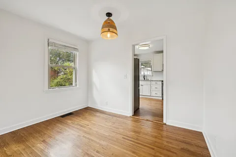 an empty room with wooden floor mirror and window