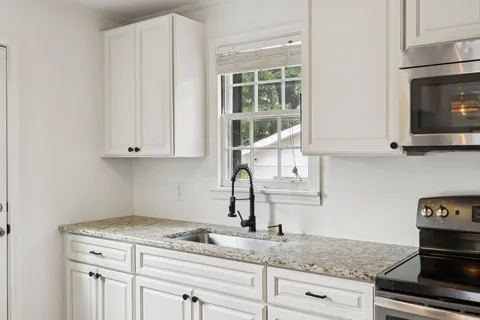 a kitchen with granite countertop a stove and a white cabinet