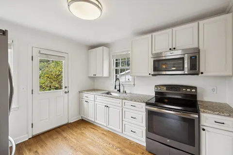 a kitchen with stainless steel appliances granite countertop a stove a sink and a microwave