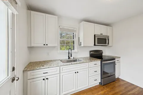 a kitchen with granite countertop white cabinets stainless steel appliances and a sink