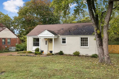 a view of a yard in front of a house with large tree