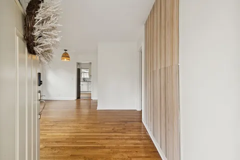 a view of a hallway with wooden floor and a bathroom