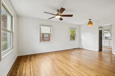 a view of empty room with wooden floor and fan