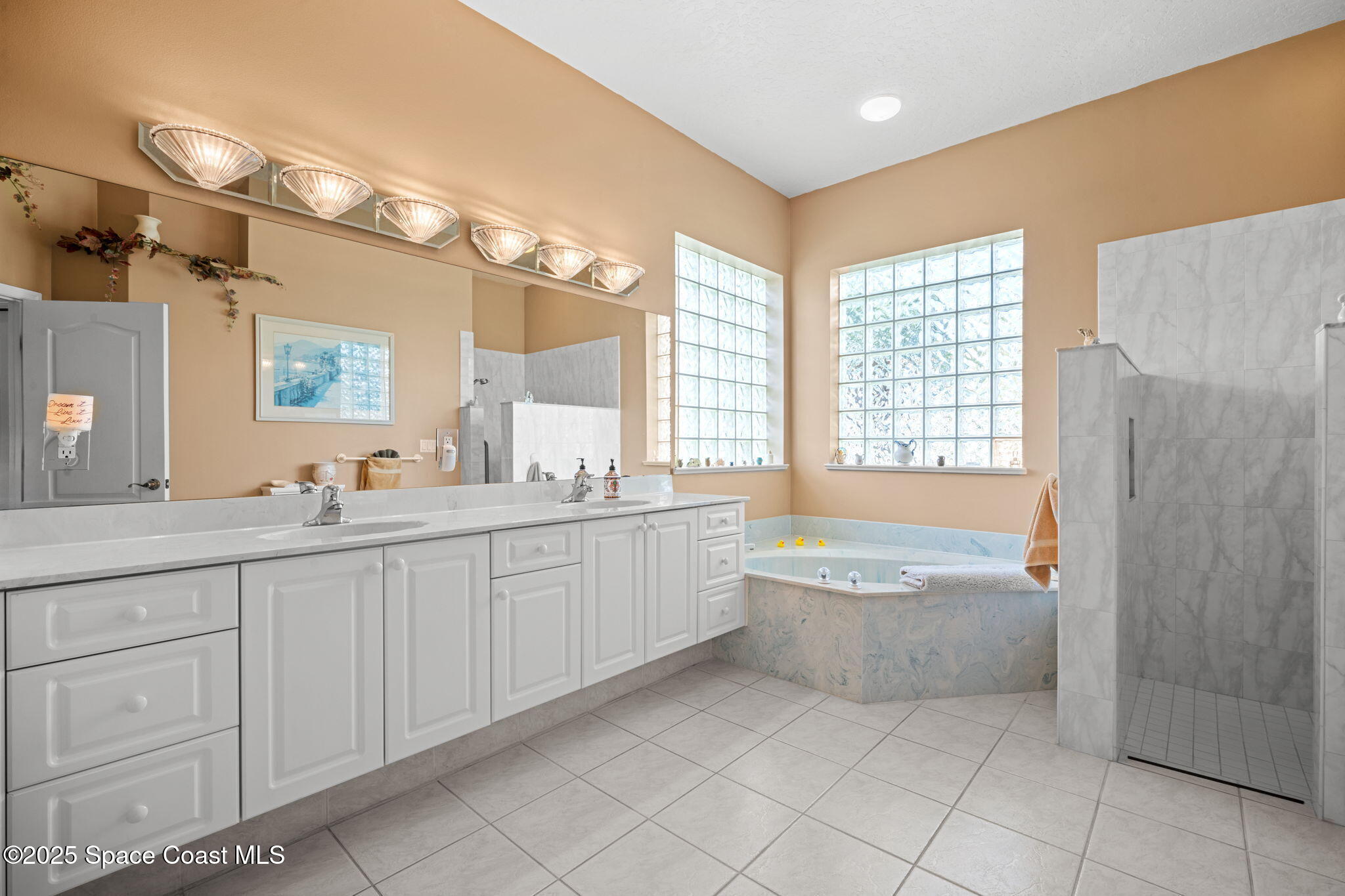 415 Indian Bay Boulevard Merritt Island, FL 32953 - Photo 18 of 37 a spacious bathroom with a double vanity sink a large mirror and a bathtub