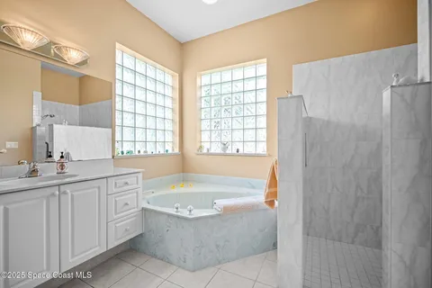 a spacious bathroom with a double vanity sink a large mirror and a bathtub