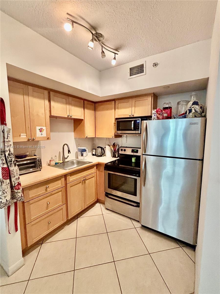 2630 Southwest 28th Street, Unit 34 Miami, FL 33133 - Photo 8 of 26 a kitchen with granite countertop a refrigerator and a stove top oven