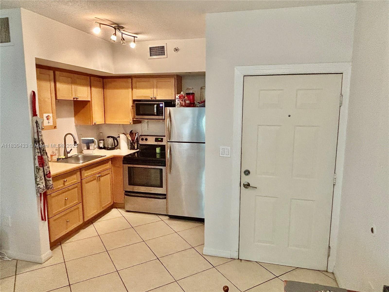 2630 Southwest 28th Street, Unit 34 Miami, FL 33133 - Photo 9 of 26 a kitchen with stainless steel appliances granite countertop a refrigerator and a sink