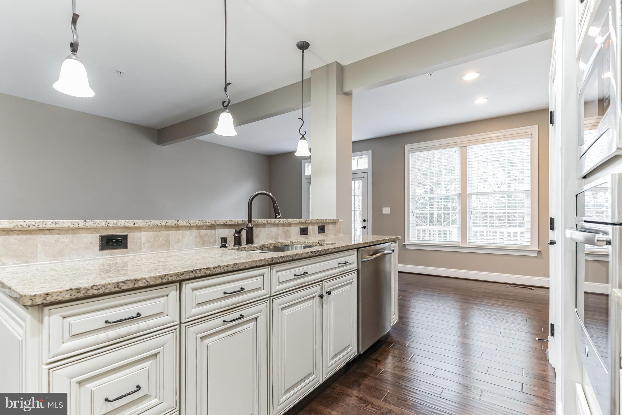 4927 Collingtons Bounty Drive Bowie, MD 20720 - Photo 4 of 38 a kitchen with a sink dishwasher and white cabinets with wooden floor