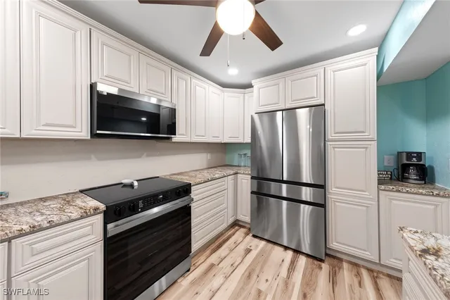 a kitchen with granite countertop a refrigerator stove top oven and sink
